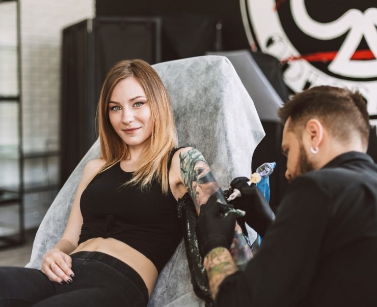 Smiling tattooed girl looking in camera professional tattooer do