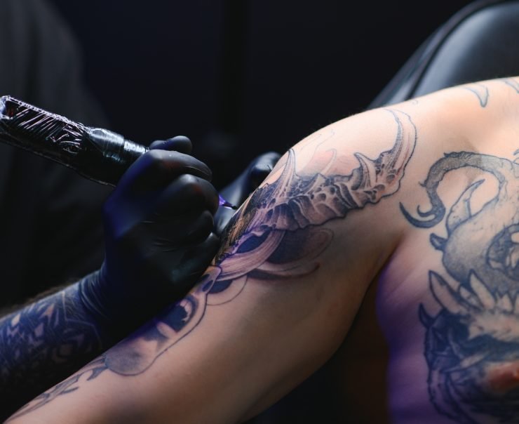 Tattoo artist hands wearing gloves and holding a tattoo machine